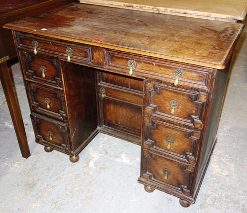 A 20th century oak kneehole desk with eight drawers about the knee and recessed central cupboard, 91cm wide.