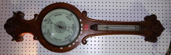 An oak wheel barometer, early 20th century, with foliate scroll carved embellishment and thermometer over a later ten inch white dial detailed 'J.B. D