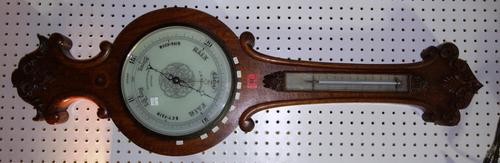 An oak wheel barometer, early 20th century, with foliate scroll carved embellishment and thermometer over a later ten inch white dial detailed 'J.B. D