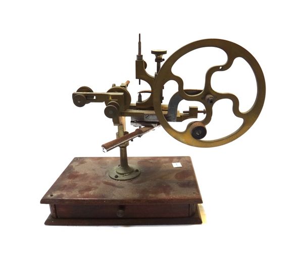 A brass watch maker's cutting lathe, with manual fly wheel and an arrangement of adjustable chucks, on a rectangular stained pine base, with frieze dr