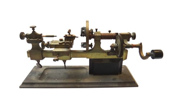 A brass and iron watch maker's lathe, probably Swiss, with manual handle, adjustable chuck and various adjustable stages, on a rectangular iron base,