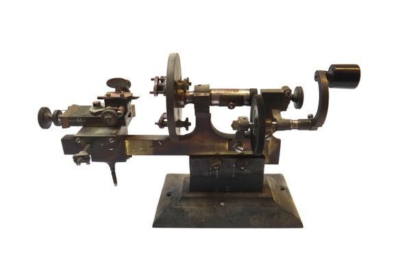A brass and steel watch maker's lathe, probably Swiss, with manual handle, adjustable chuck and stage, on a rectangular metal base, 39cm wide.