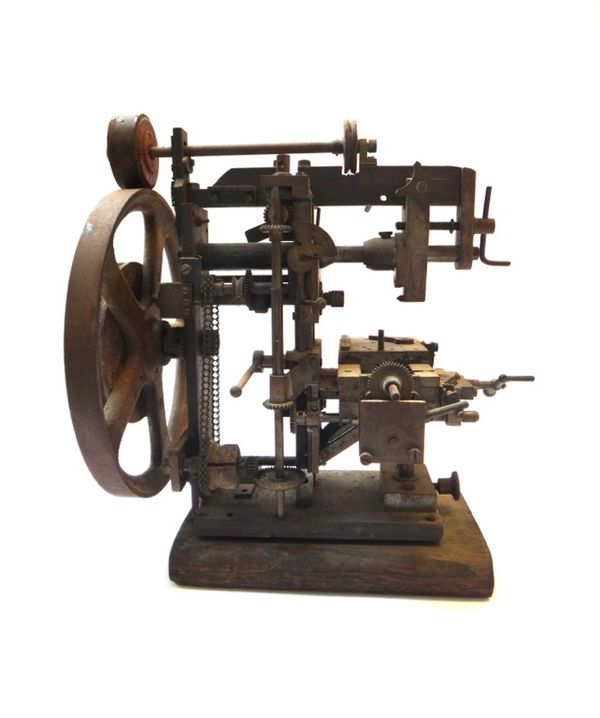 An iron and metal watch maker's lathe, with a large pulley wheel, a chain driven clockwork mechanism and an adjustable stage, 33cm high.