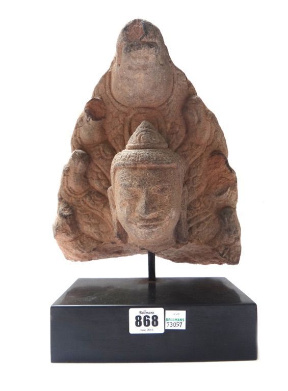 A 17th century Tibetan stone partial figure head, on a black rectangular polished slate plinth, 32cm high overall.