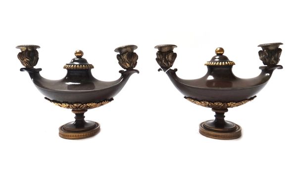 A pair of Empire style patinated bronze twin branch candelabra, 19th century, each of oil lamp form with central circular cover and gilt embellishment