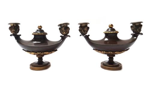 A pair of Empire style patinated bronze twin branch candelabra, 19th century, each of oil lamp form with central circular cover and gilt embellishment