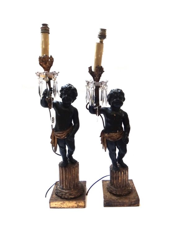 A pair of ebonised and giltwood figural table lamp lustres, 19th century, each carved as a putti atop a Corinthian column base, 60cm high excluding fi