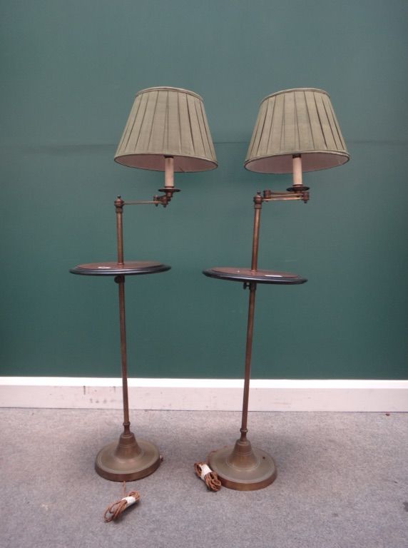 A pair of brass adjustable standard lamps, 20th century, with jointed arm and circular mahogany table to the upright, on a loaded circular foot, with