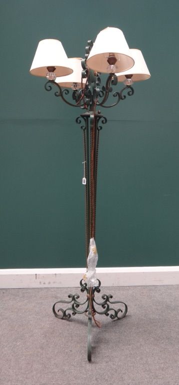 A green painted four branch wrought iron standard lamp, 20th century, with clear cut crystal sconces over scrollwork arms and a triform base, 155cm hi