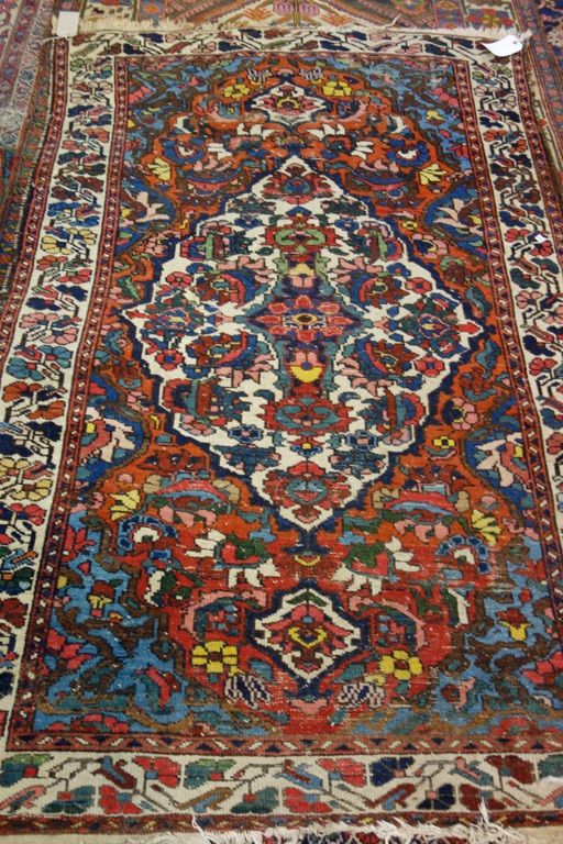 A Bakhtiari rug, Persian, the madder field with a bold ivory medallion, indigo spandrels, all with floral sprays, on ivory floral spray border, 195 x