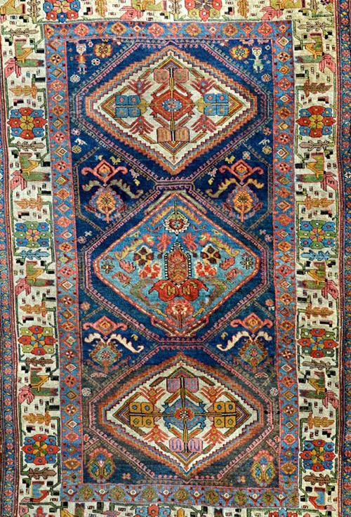 A Bidjar rug, Persian, the dark indigo field with an indigo and two ivory diamonds, supported by pairs of flowering plants, minor motifs and two figur