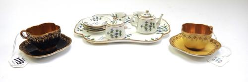 Two Coalport miniature gilt cabinet cups of quadralobe form, circa 1900, one blue and the other yellow, with green printed marks, together with a Mint