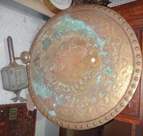 A large embossed brass circular charger and a brass wall lantern.