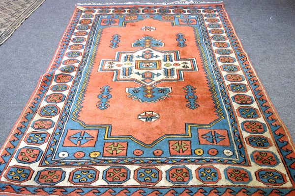 A Turkish rug, the pink field with an ivory medallion, 226cm x 168cm.