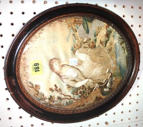 An oval silkwork tapestry depicting a seated lady and a framed map.