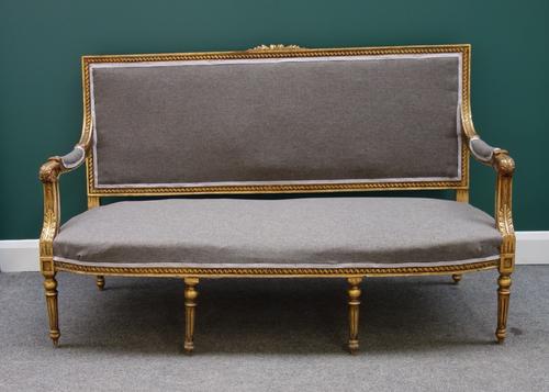 A Louis XVI style gilt canape/sofa with floral crest and open arms on tapering reeded supports, 158cm wide.