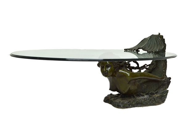 A 20th century coffee table, the oval glass top on a bronze base formed as a mermaid, 136cm wide.  Illustrated