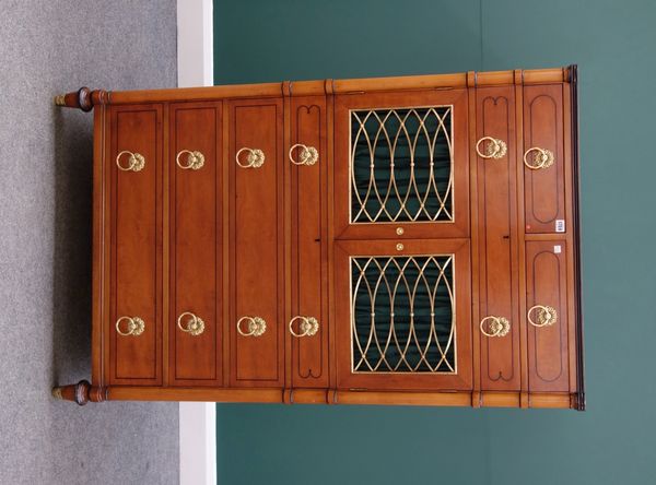 An early 20th century American satinwood side cabinet, with two short over one long drawer, over a pair of brass grille doors, enclosing three trays a