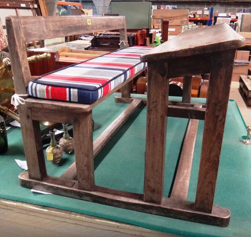 An Early 20th century hardwood double seated school desk of diminutive form, solid seat and rest on dual standard ends united by stretchers, 100cms wi