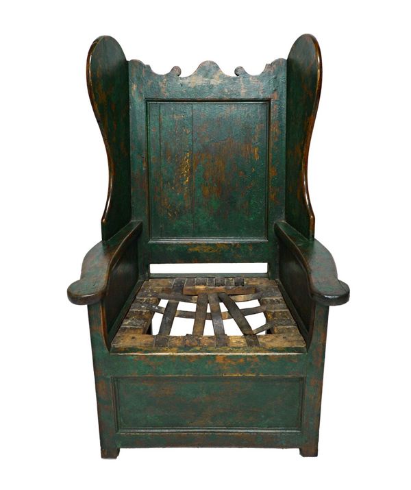 An 18th century green painted oak panelled wingback lambing chair, on block supports, 116cm wide.  Illustrated