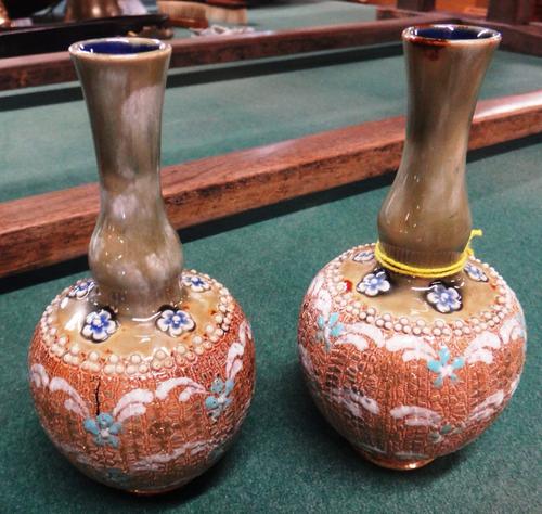 A pair of Royal Doulton small stoneware vases, each with pinched elongated neck above textured body with blue and white floral spray decoration, impre