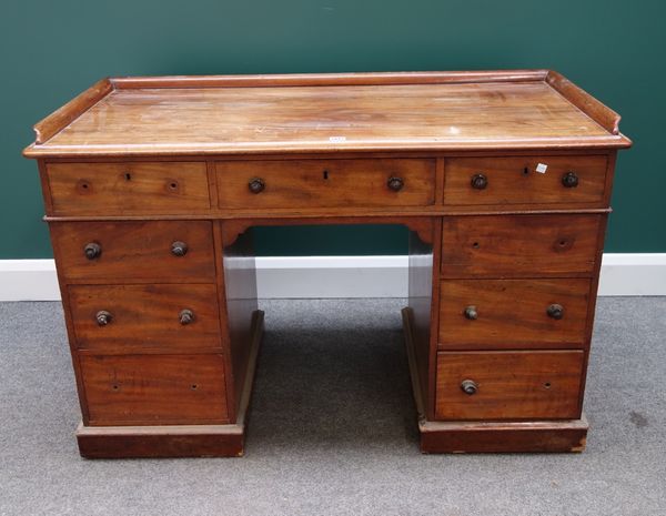 A Victorian mahogany writing desk with galleried top over nine drawers about the knee on plinth base, 122cm wide .