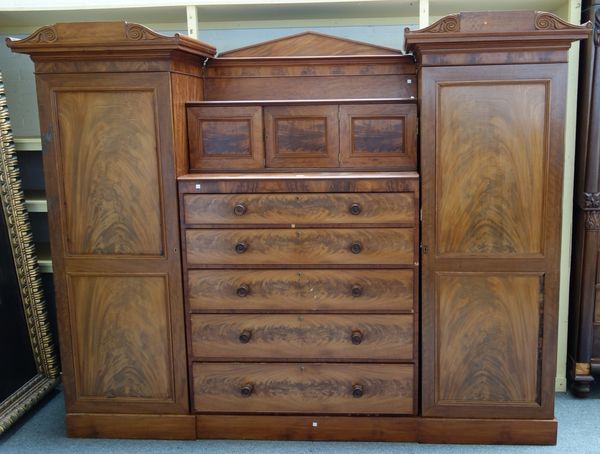 An early 19th century mahogany Sentry compactum wardrobe, the pair of full length hanging cupboards flanking three small cupboards over five long draw