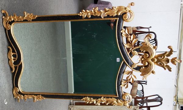 An 18th century Italian style parcel gilt ebonised wall mirror, with interlaced acanthus scroll crest and floral chased frame about the shaped mirror