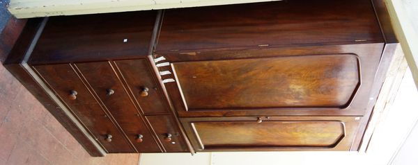 A 19th century mahogany linen press, with pair of arch panel doors enclosing five trays, over two short and three long graduated drawers, on plinth ba