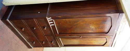 A 19th century mahogany linen press, with pair of arch panel doors enclosing five trays, over two short and three long graduated drawers, on plinth ba
