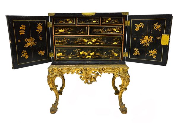 An early 20th century black lacquer chinoiserie decorated cabinet, the pair of doors enclosing seven drawers, on a 19th century pierced and acanthus c