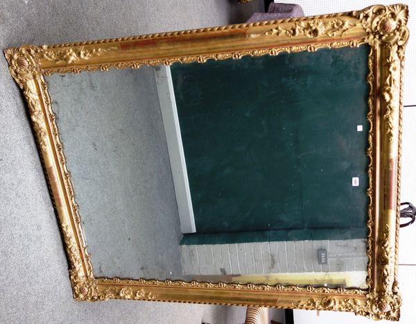 A 19th century gilt framed rectangular wall mirror with shell and floral moulded corners about the mirror plate, 125cm wide x 126cm high.