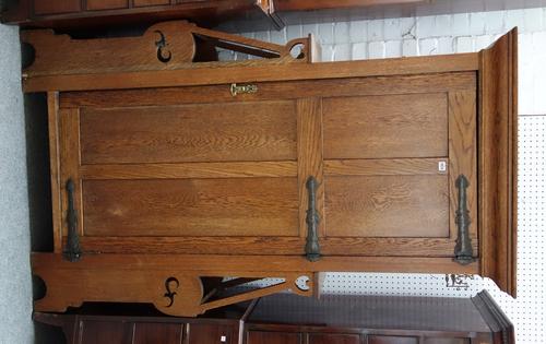 An Art Nouveau oak hall cupboard with panel door flanked by pair of stick stands, 121cm wide x 195cm high.