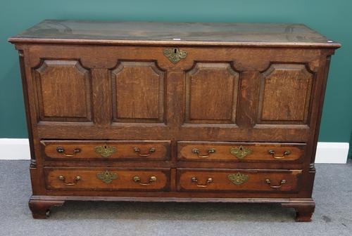 A mid 18th century crossbanded oak mule chest, the lift top over a four panel front and four short drawers flanked by reeded rounded corners on ogee b