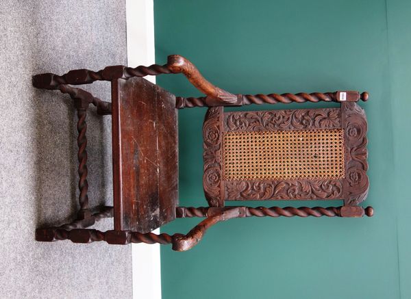 A 17th century oak and beech open armchair with cane back and solid seat on barley-twist support.