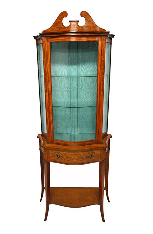 An Edwardian marquetry inlaid satinwood display cabinet, the swan neck cornice over serpentine glazed door and single drawer, on splayed square suppor
