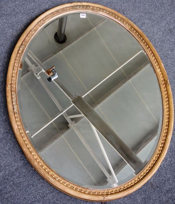 An early 20th century gilt framed oval wall mirror with ribbon tied reeded frame, 85cm wide x 110cm high.