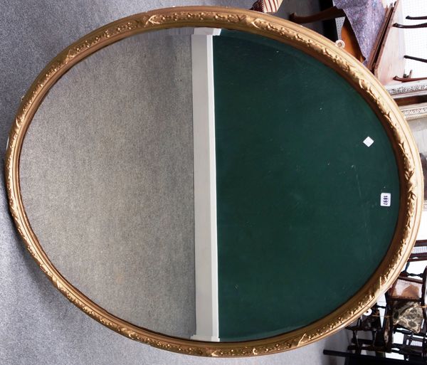 A late 19th century gilt framed oval wall mirror with ribbon tied moulded decoration about the bevelled mirror plate, 108cm wide x 132cm high.