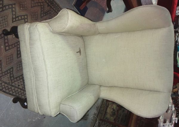 A cream upholstered wing armchair.