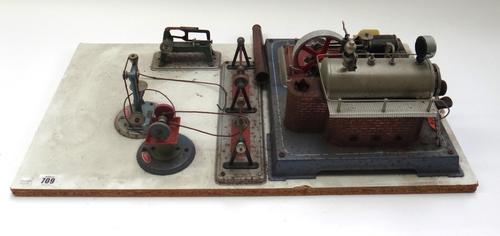 A Wilesco steam engine and fly wheel, board mounted and with grinding stone, pillar drill and chop saw.