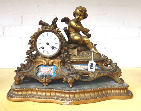 A French gilt spelter and porcelain inset figural mantel clock, late 19th century, with an ormolu Cupid figure surmounted over a scroll cast case with