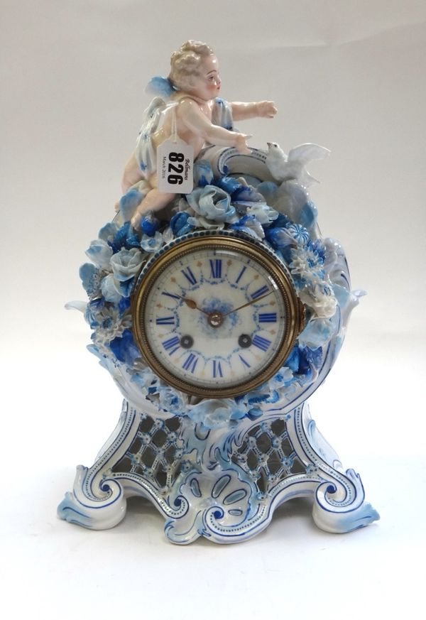A French porcelain mantel clock, early 20th century, surmounted with a cherubic figure and a dove, over a foliate encrusted and pierced latticework bo