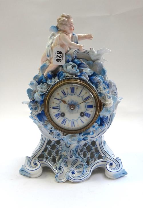A French porcelain mantel clock, early 20th century, surmounted with a cherubic figure and a dove, over a foliate encrusted and pierced latticework bo