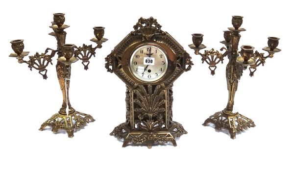A gilt brass mantel clock garniture, circa 1900, the angular case cast with peacock and foliate masks with matching five branch candelabra garnitures,