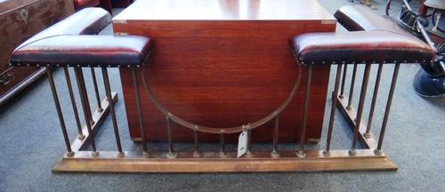 An English brass club fender, early 20th century, re-upholstered in red leather, 148.5cm wide x 59cm high x 63cm deep.