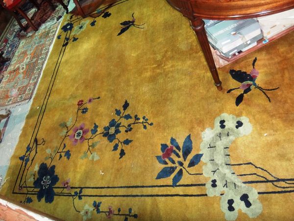 A Chinese carpet, circa 1930, with yellow ground, flowers and a butterfly.