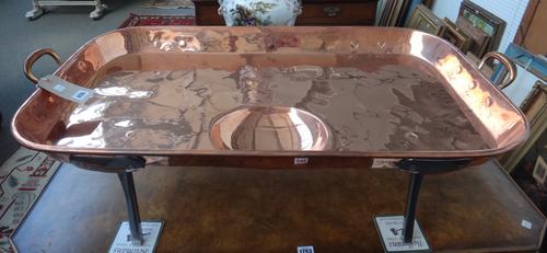 A large Victorian copper meat serving tray, late 19th century, the rectangular tray with a gravy well and bell metal handles on steel legs, 102cm acro