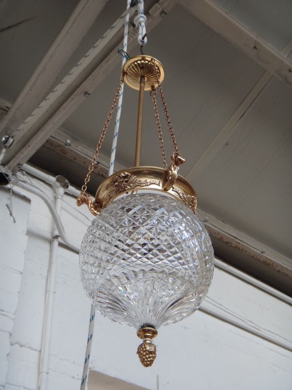 A gilt brass and cut glass ceiling light, 20th century, the ceiling boss over three linked chains suspending a foliate cast rim over a cut glass circu