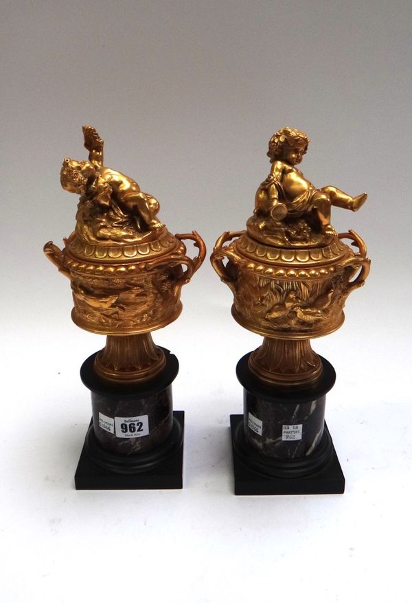 A pair of omolu and marble garnitures, late 19th century, cast with deer and game birds, the covers cast with drunken putti, the two handled body over
