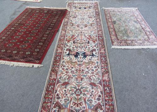 An Indian runner, the ivory field with huntsmen, animals and plants, a madder border, 500cm x 73cm, together with an Indian silk prayer rug, pale indi